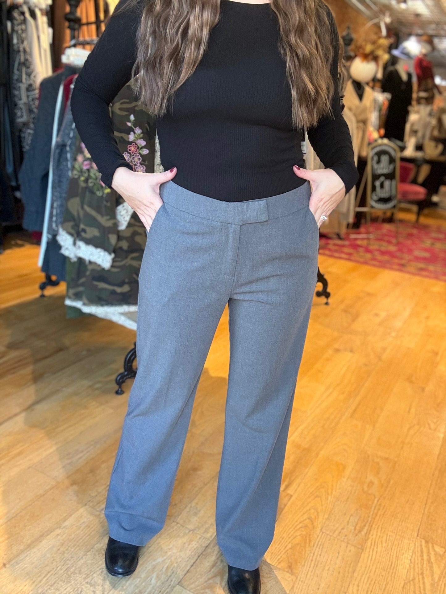 Person wearing a black top and gray pants in a clothing store.
