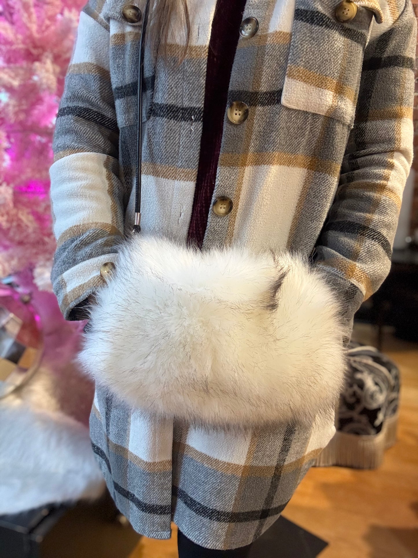 Person wearing a plaid coat with a fluffy white handbag.