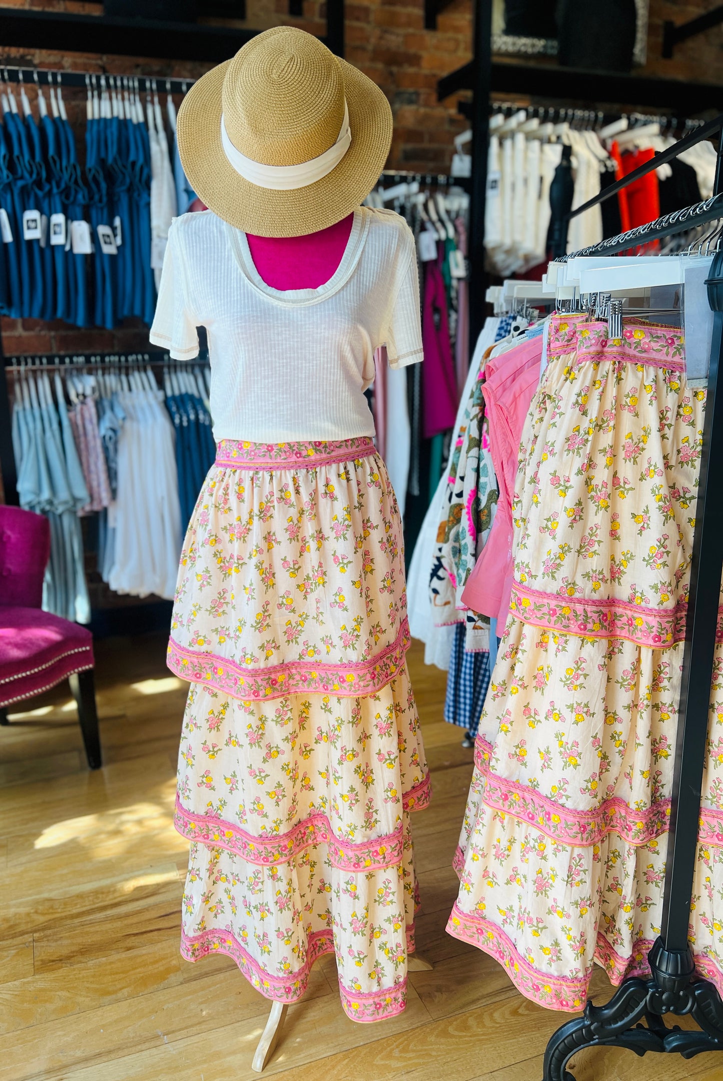 Mannequin wearing a floral dress with a hat in a clothing store setting