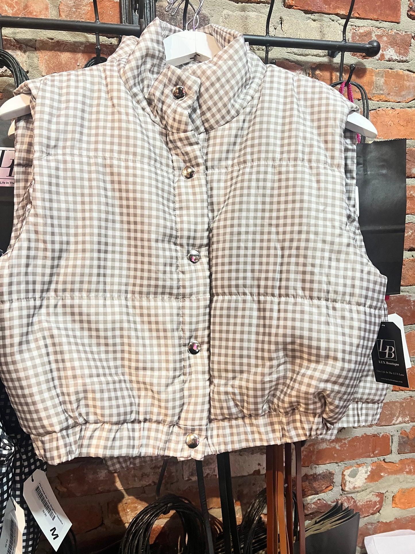 Taupe and white cropped fit puffer vest with snap closures and stretchy waistband.