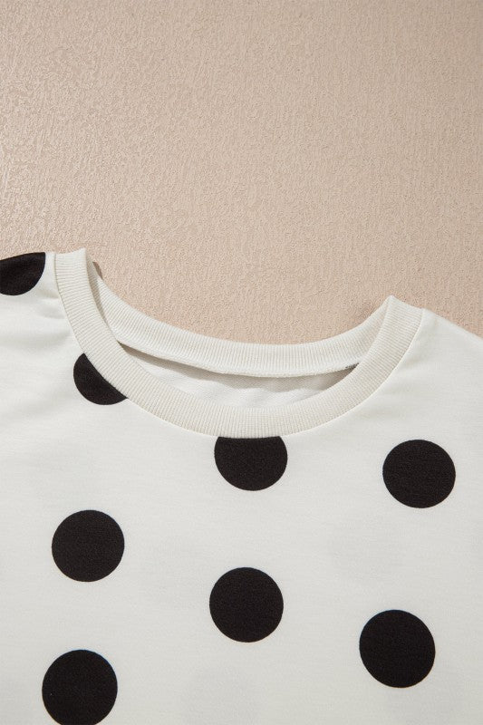 White top with black polka dots on a beige background