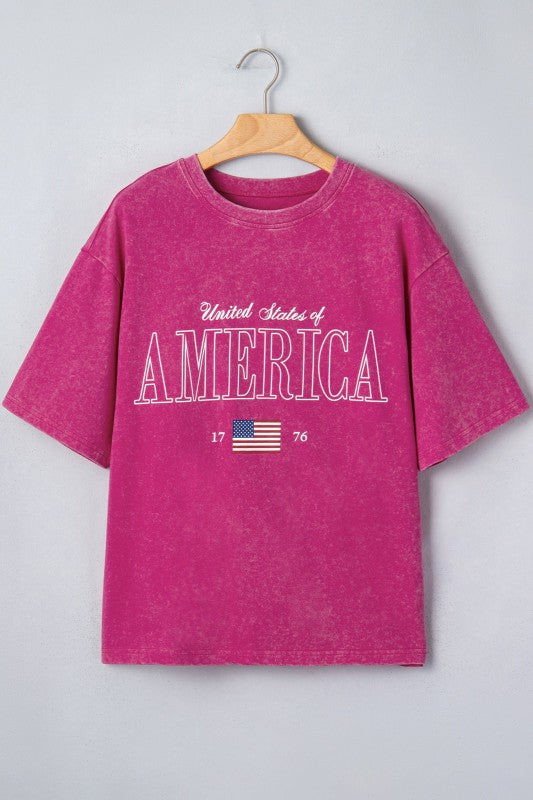 Pink t-shirt with 'United States of America' text and flag on a hanger against a light gray background