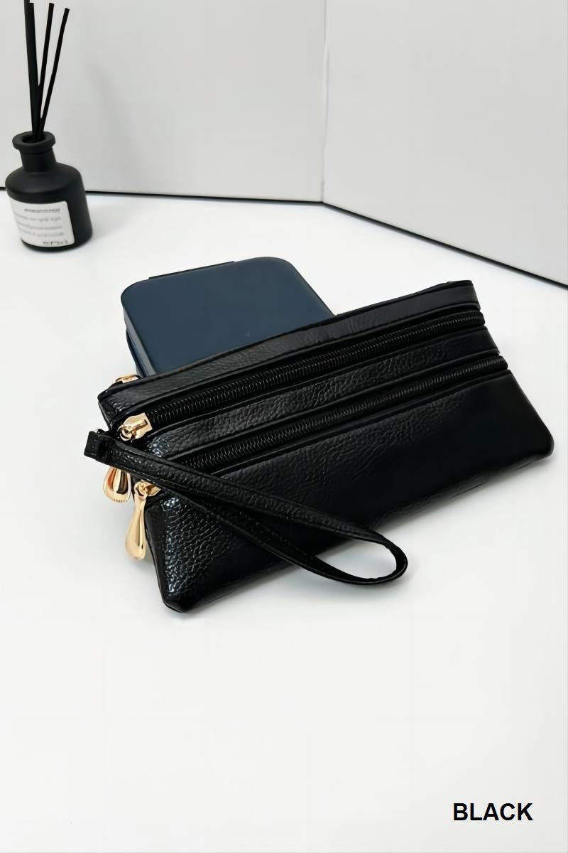 Black leather clutch with gold zippers on a white surface