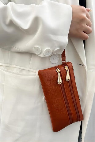Brown leather wallet with gold zipper held by a person wearing a white coat.