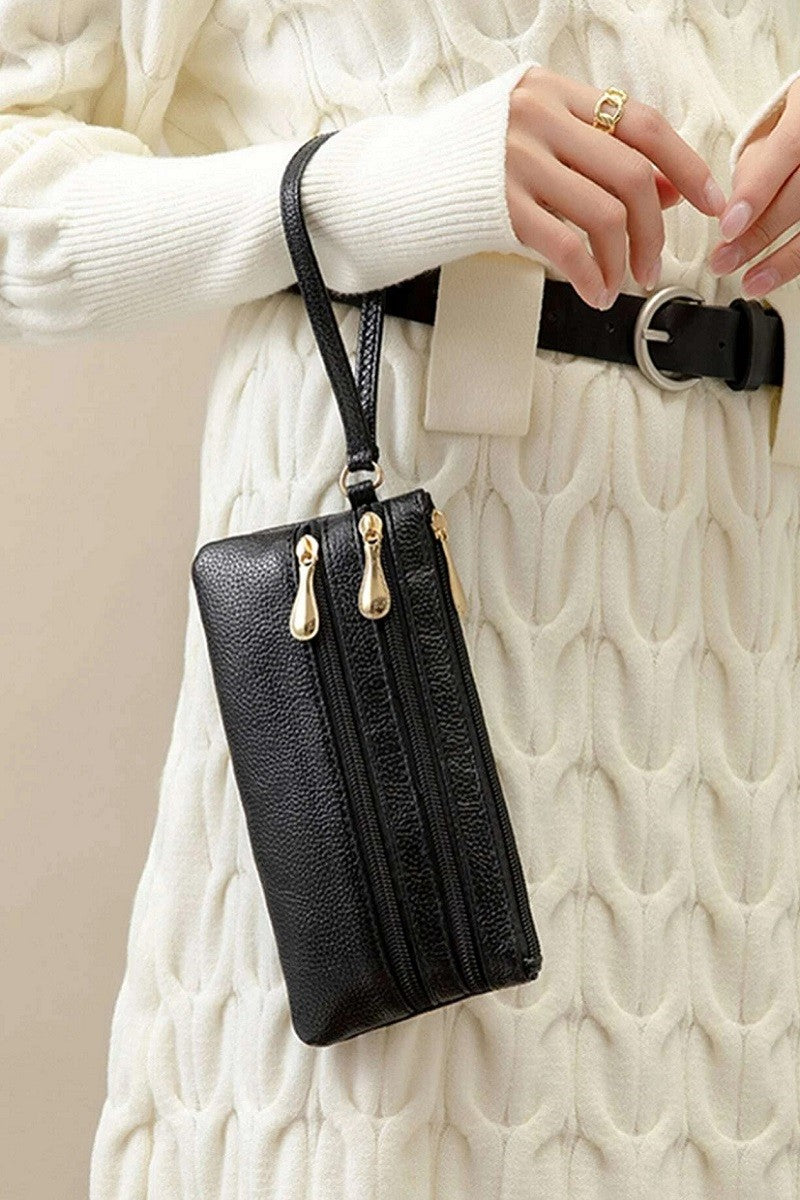 Black leather wallet with gold zipper on a white textured background
