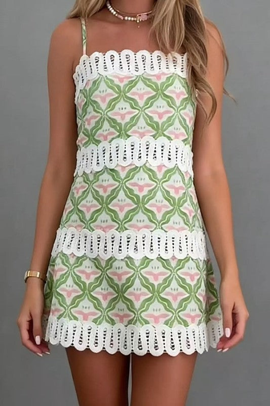 Woman wearing a green and pink patterned dress with white lace details on a gray background