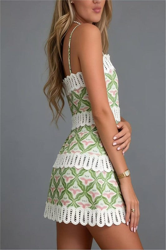 Woman wearing a green and white patterned dress with lace details on a gray background