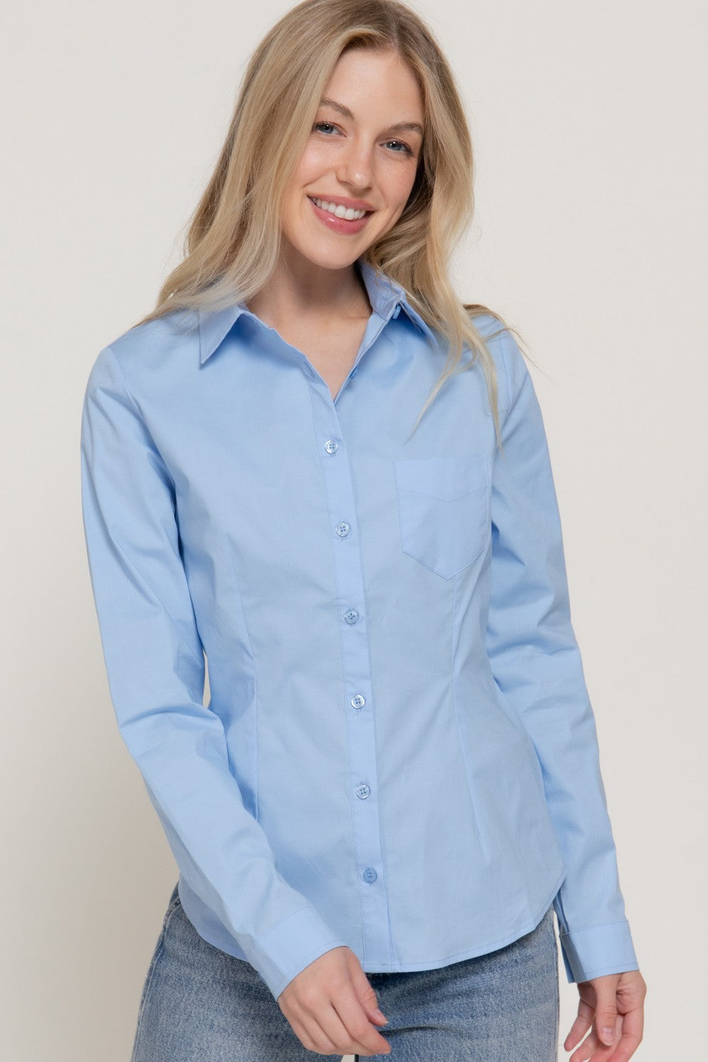Woman wearing a light blue button-up shirt against a plain background