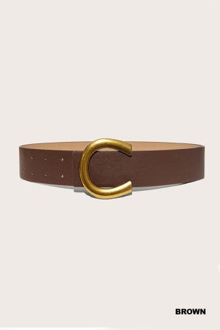 A brown leather belt with a large, polished gold-tone C-shaped buckle, presented on a light beige background with the word 'BROWN' printed in the bottom right corner.
