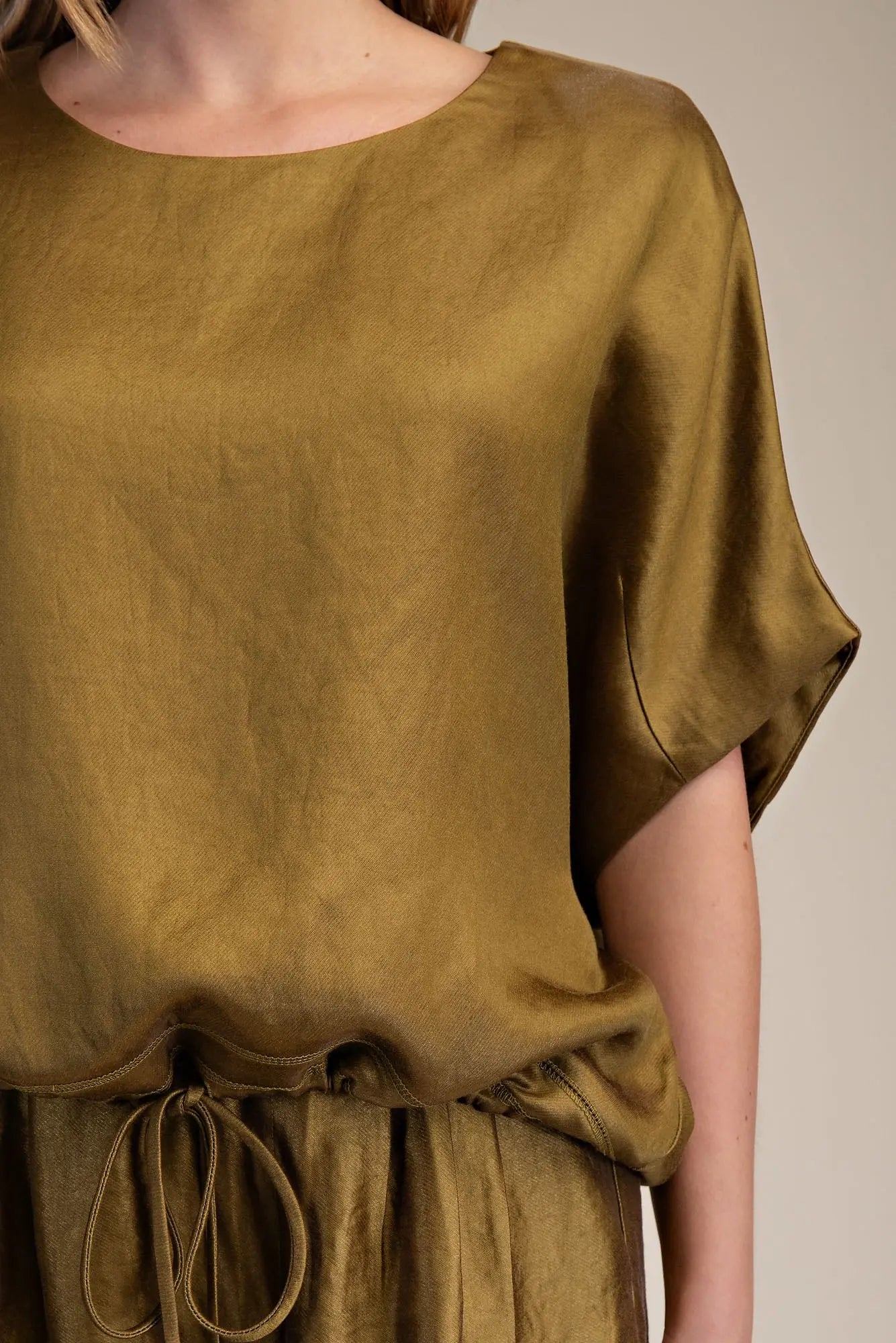 Olive green top worn by a person on a neutral background