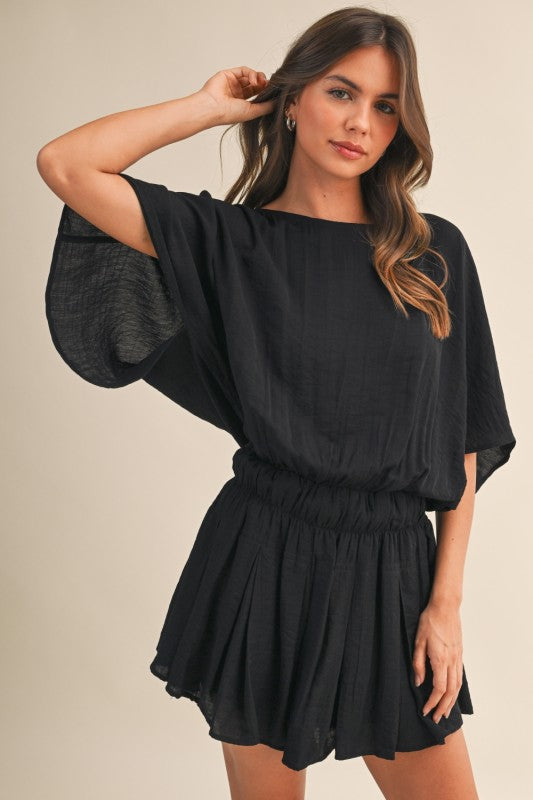 Woman wearing a black romper against a beige background