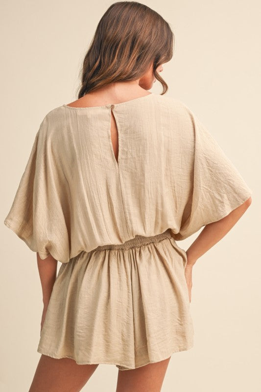 Beige romper worn by a person on a beige background