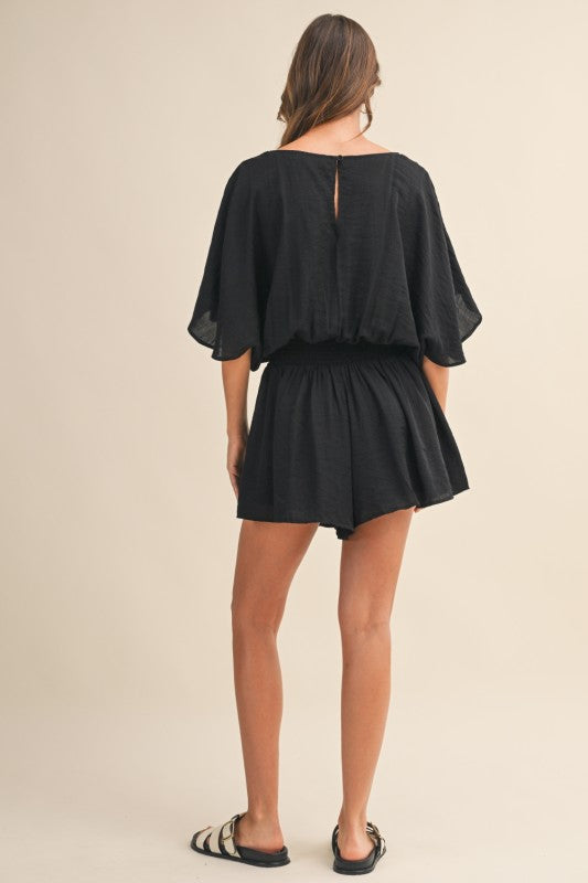 Woman wearing a black romper on a beige background