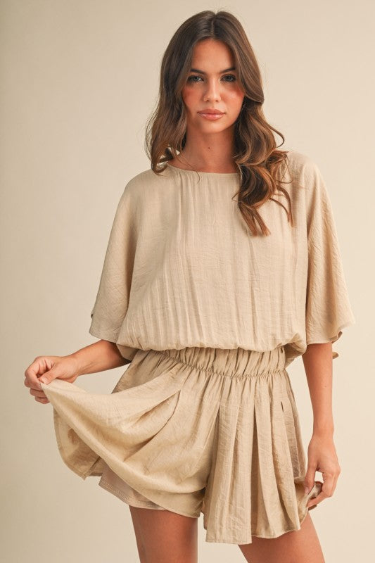 Woman wearing a beige outfit against a plain background