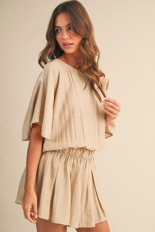 Woman wearing a beige outfit against a plain background