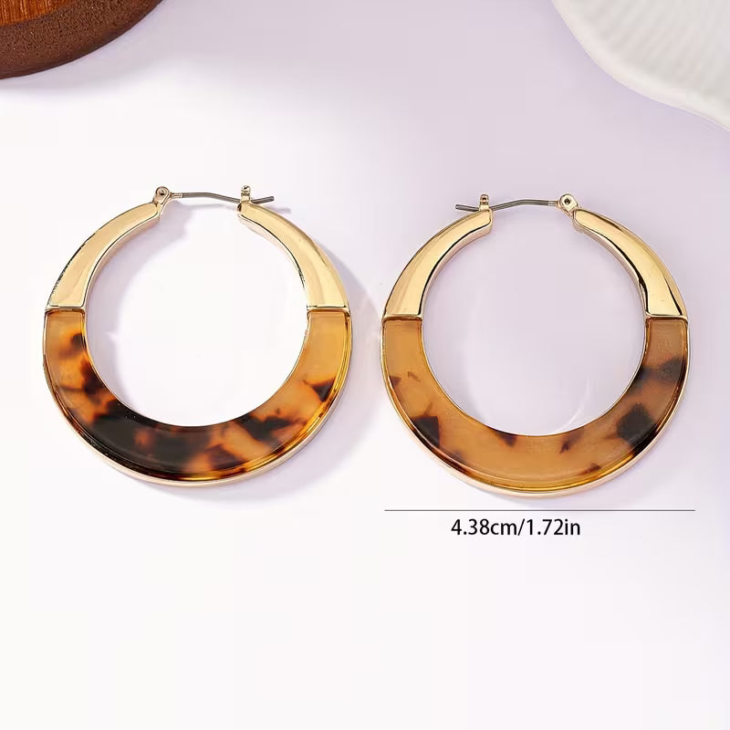 A pair of large gold-tone hoop earrings with a tortoiseshell patterned lower half, displayed on a clean white background with a size measurement overlay indicating 4.38cm (1.