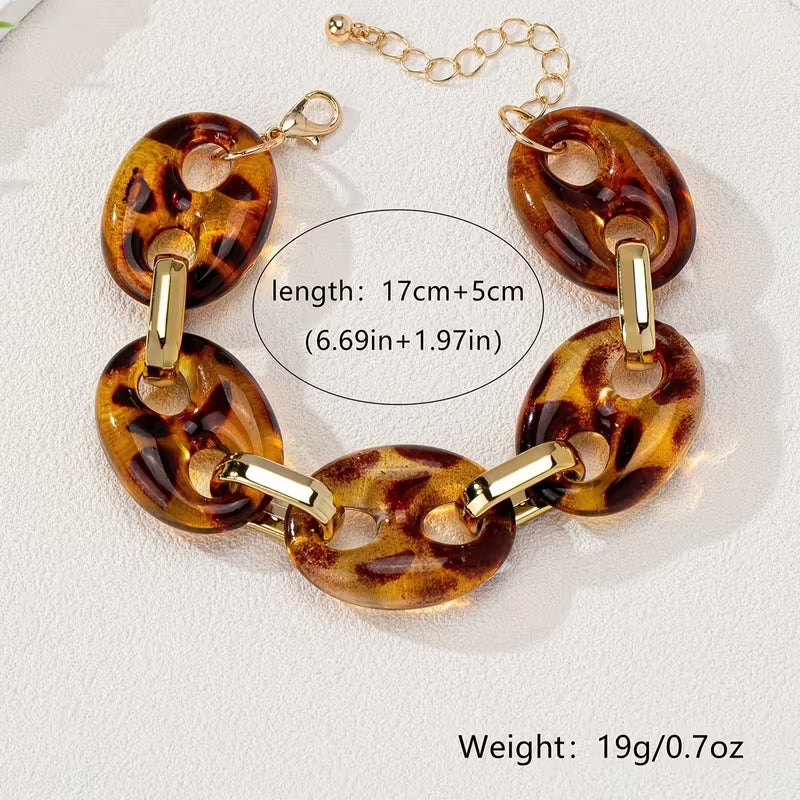 A tortoiseshell resin link chain bracelet with gold-tone hardware, displayed on a textured white surface. A black text bubble in the center indicates the length (17cm+5cm / 6.