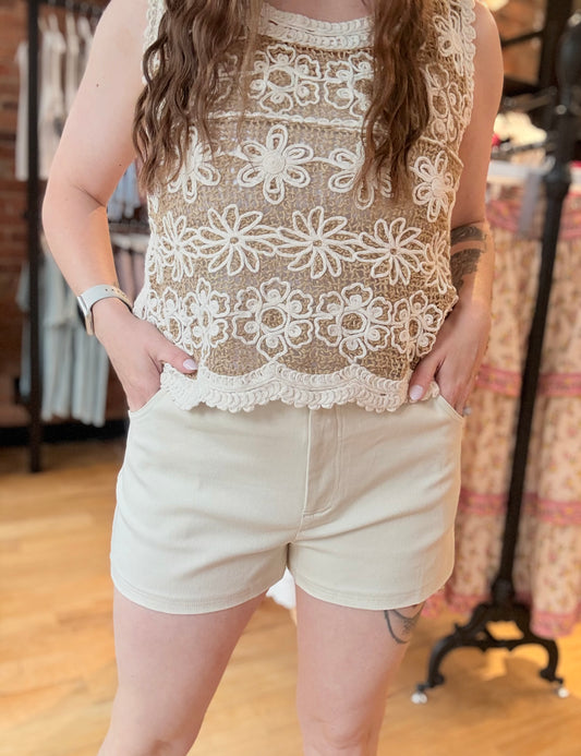 Person wearing a lace top and white shorts in an indoor setting