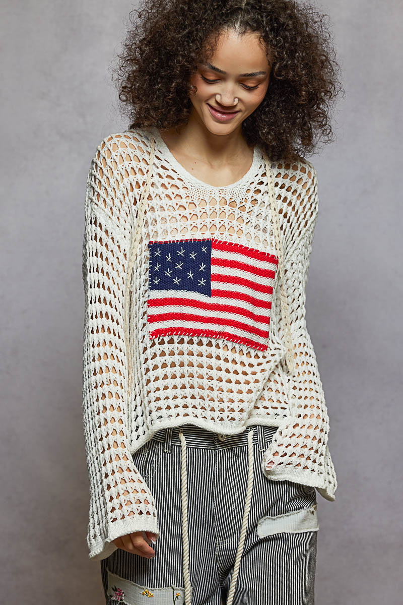 Woman wearing a crochet sweater with an American flag design on a gray background