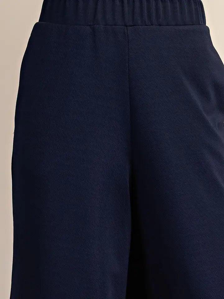 Close-up of navy blue wide-leg sweatpants showing the elastic waistband and fabric texture.