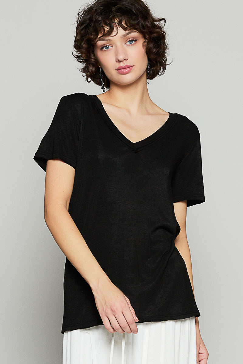 Woman wearing a black V-neck top against a plain background