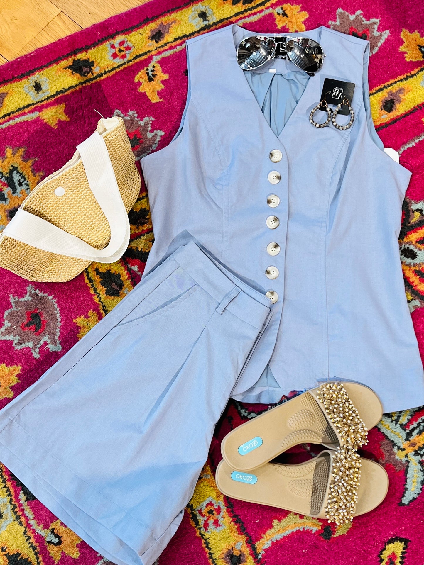 Light blue vest and pants with gold sandals on a colorful patterned rug