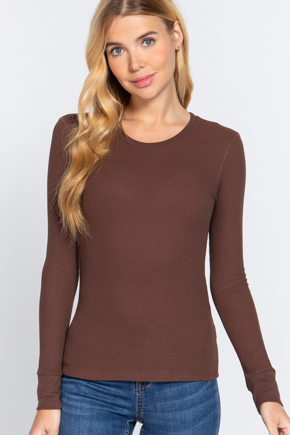 Woman wearing a brown long-sleeve top against a white background