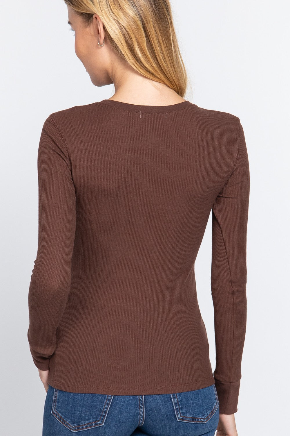 A woman shown from the back wearing a fitted, long-sleeve ribbed knit top in a medium brown color, paired with blue jeans against a plain light gray background.