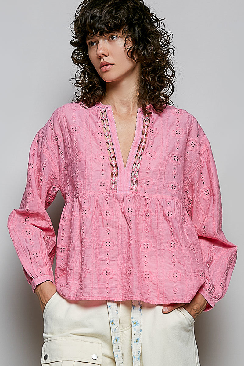 Woman wearing a pink embroidered blouse against a plain background