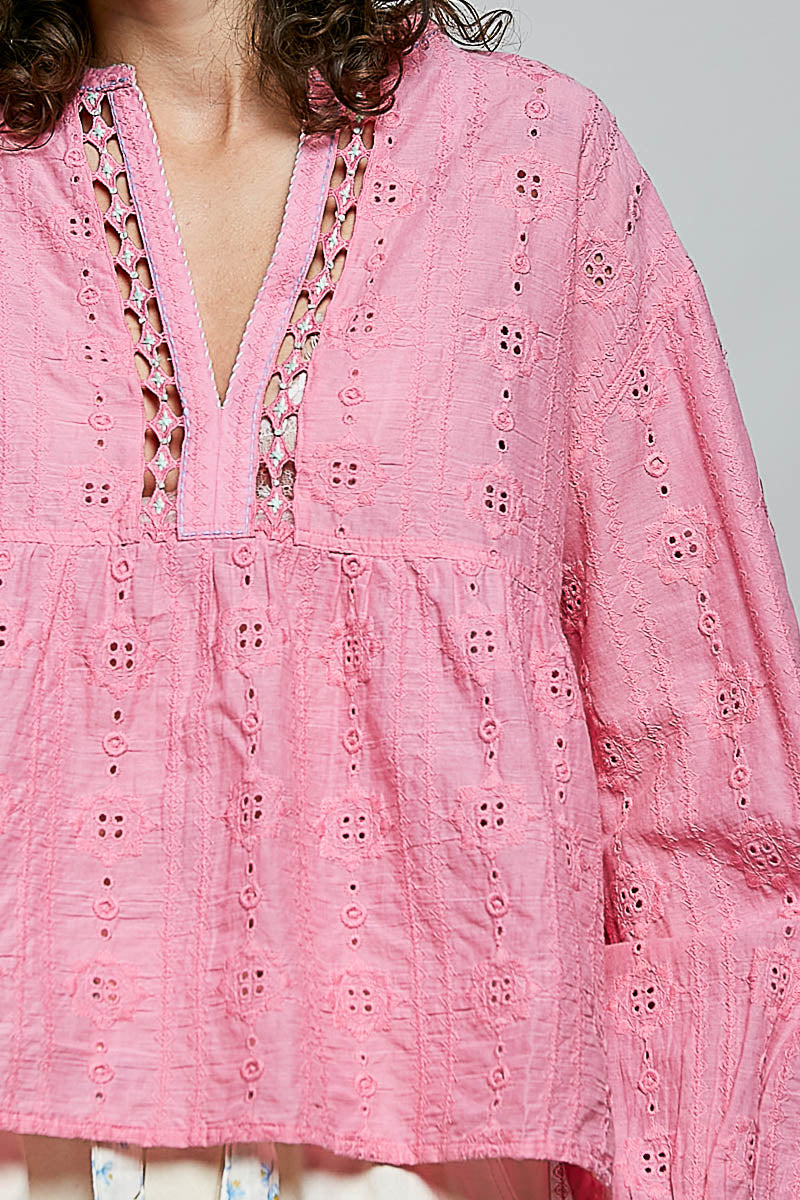 Close-up of a pink embroidered blouse with a plain background