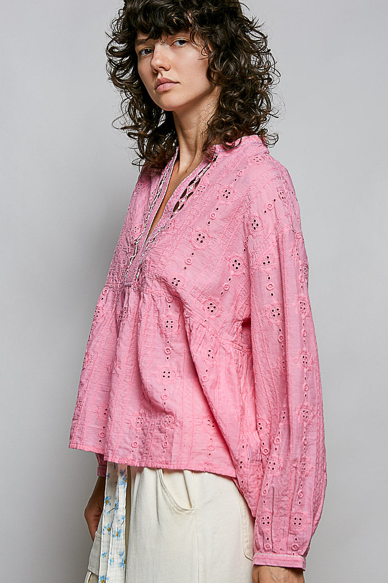 Woman wearing a pink embroidered blouse against a plain background