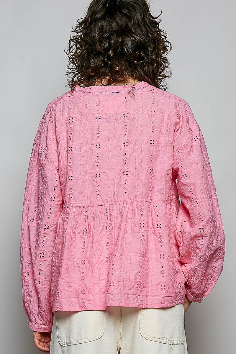 Person wearing a pink embroidered blouse with a plain background