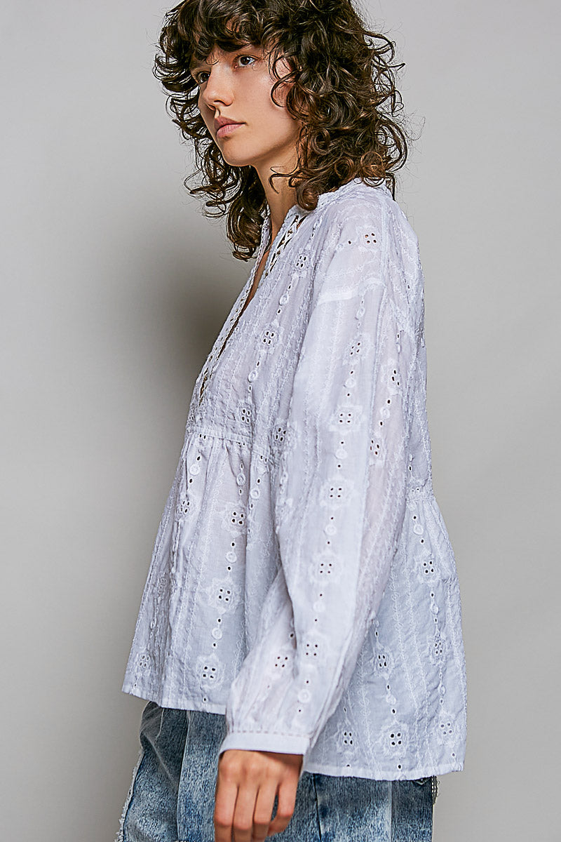 Woman wearing a light blue embroidered blouse against a plain background