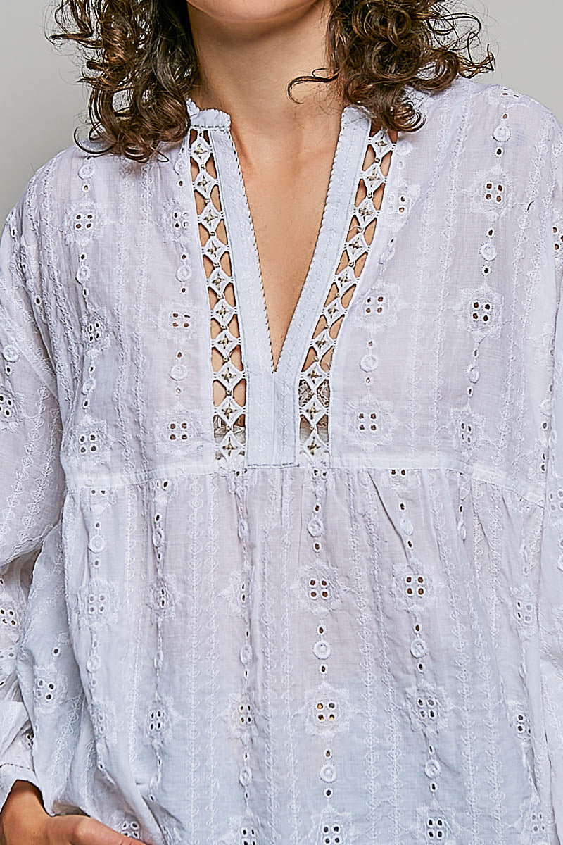 White embroidered dress with a deep neckline on a neutral background