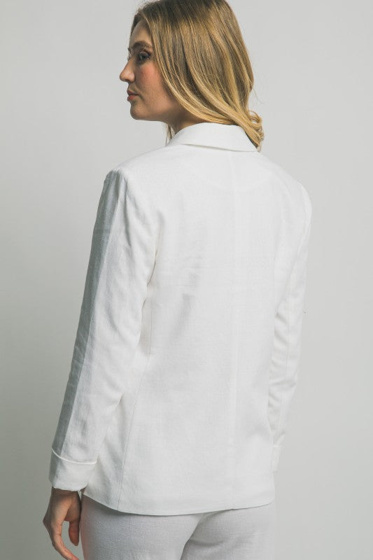 Woman wearing a white blazer with gray trim on a plain background