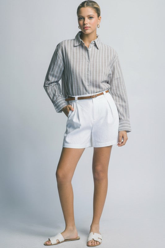 Woman wearing a striped shirt and white shorts on a plain background