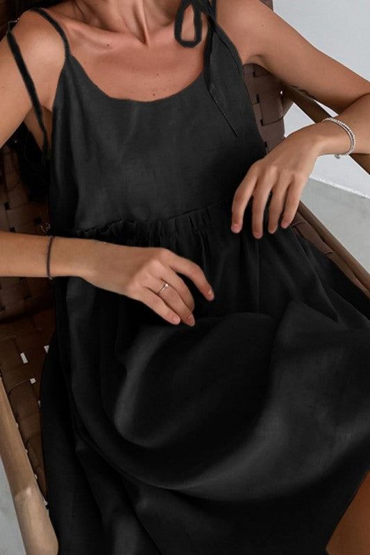 Person wearing a black dress sitting on a wooden chair.