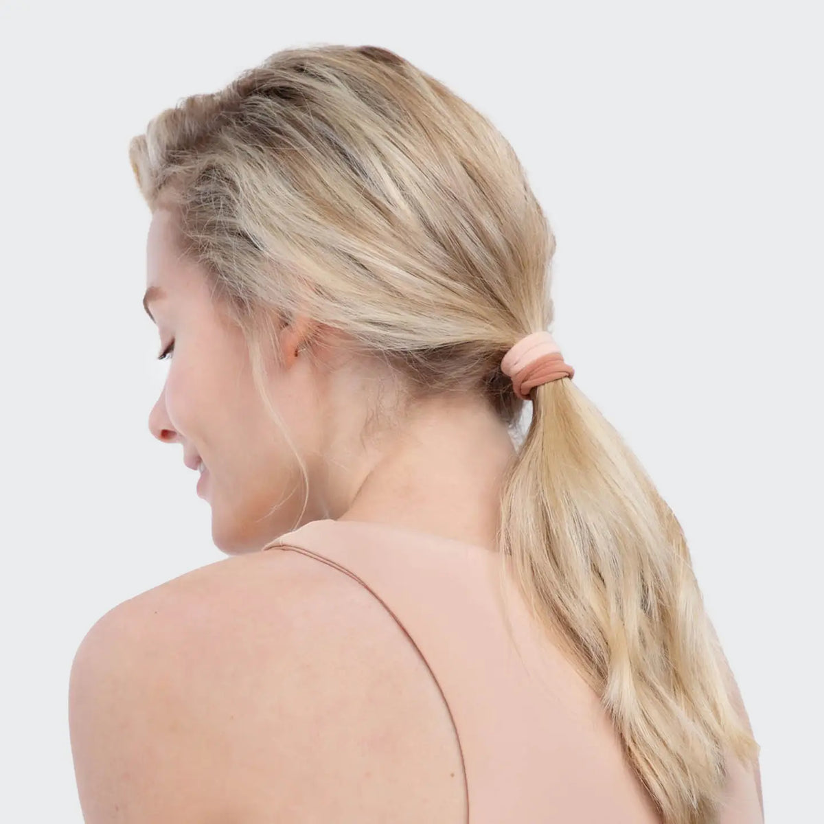 Woman with blonde hair tied in a ponytail on a white background