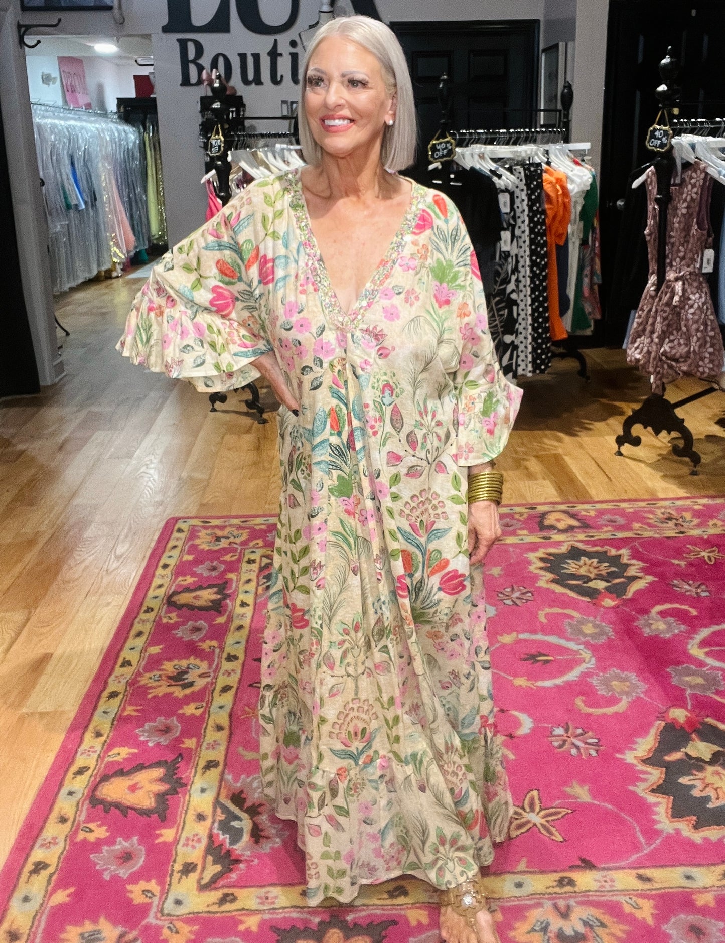 Woman in a floral dress standing on a patterned rug in a store.