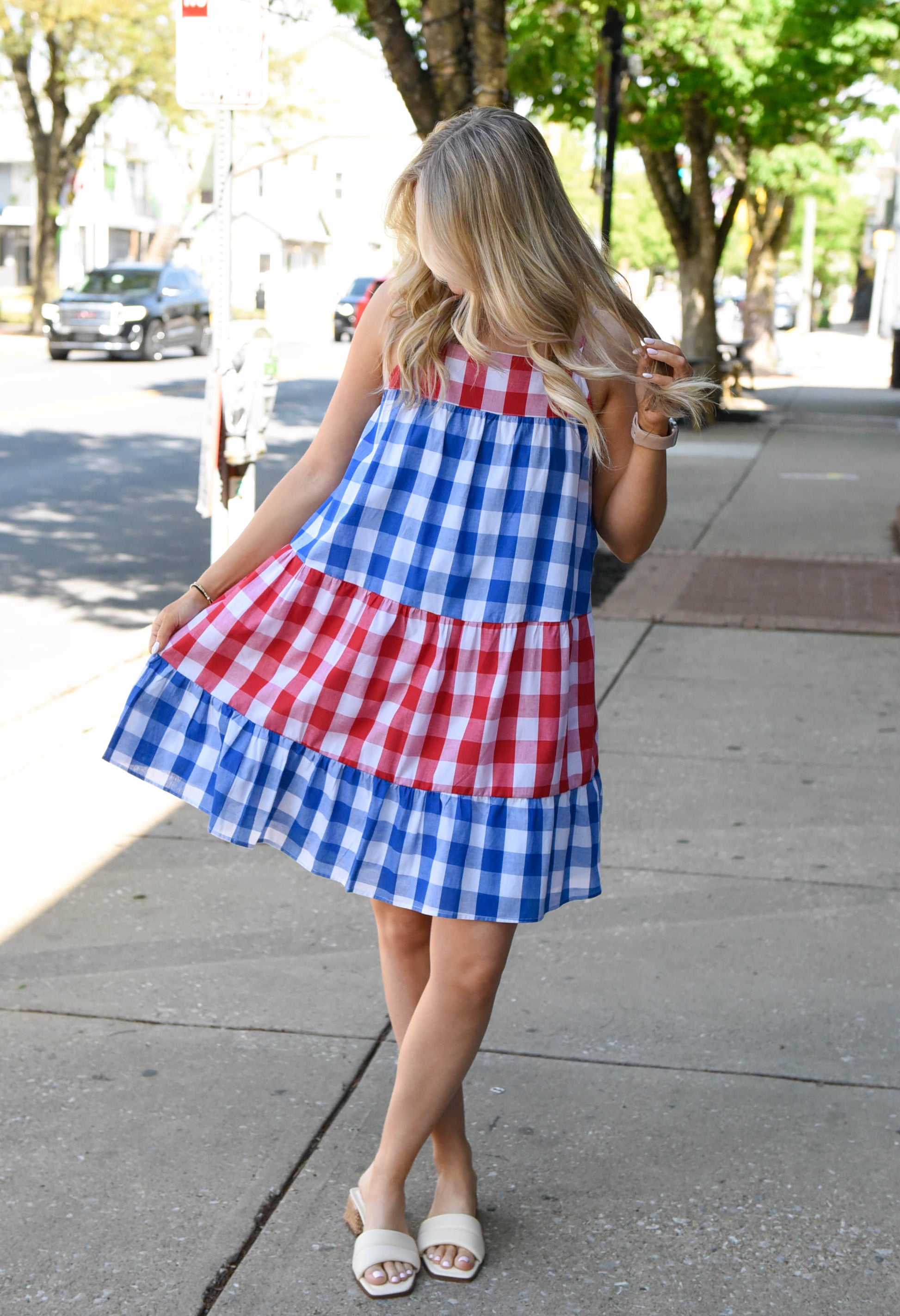 Woman wearing a red, white, and blue checkered dress on a city street.