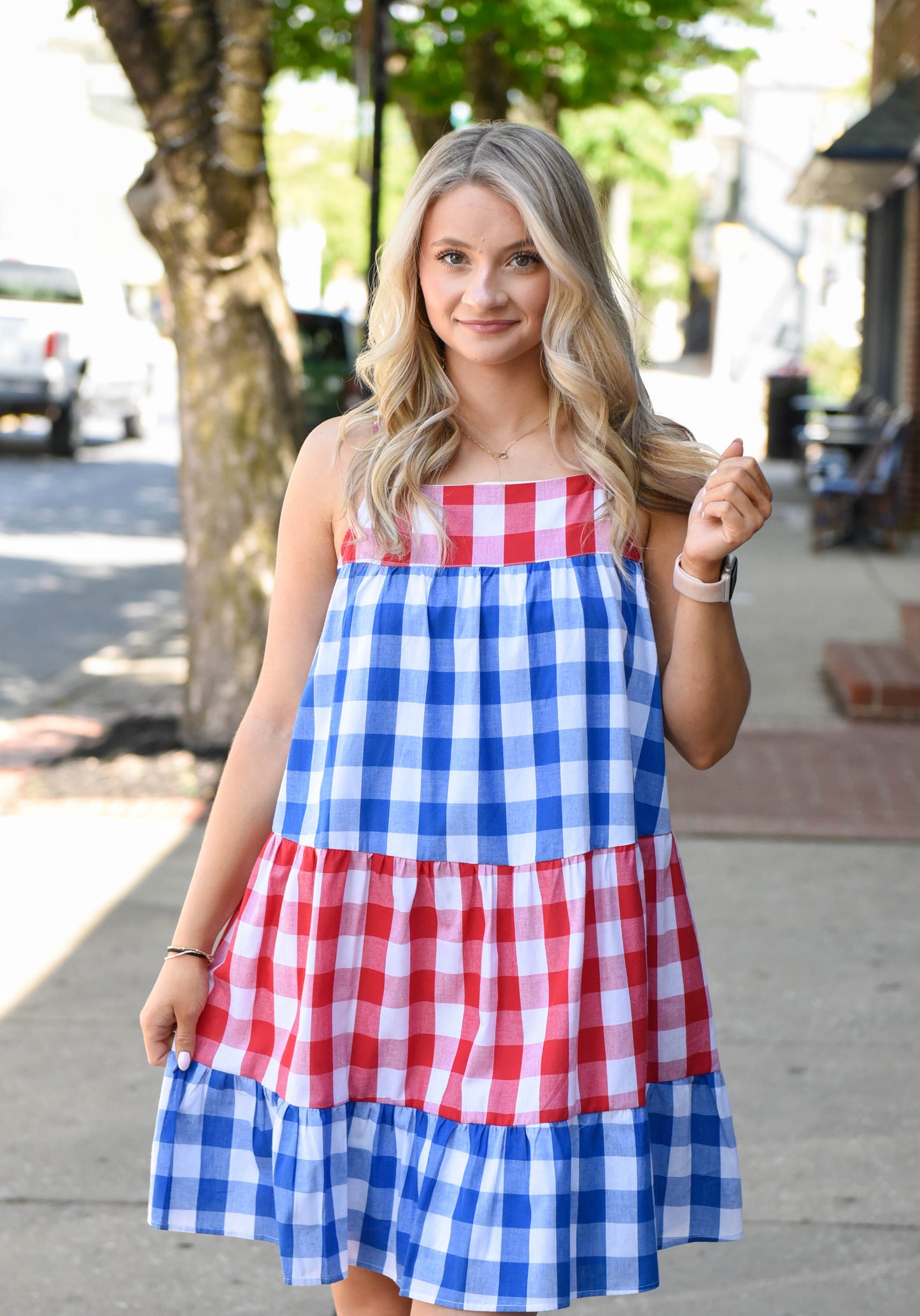 Woman wearing a red, white, and blue checkered dress on a street.