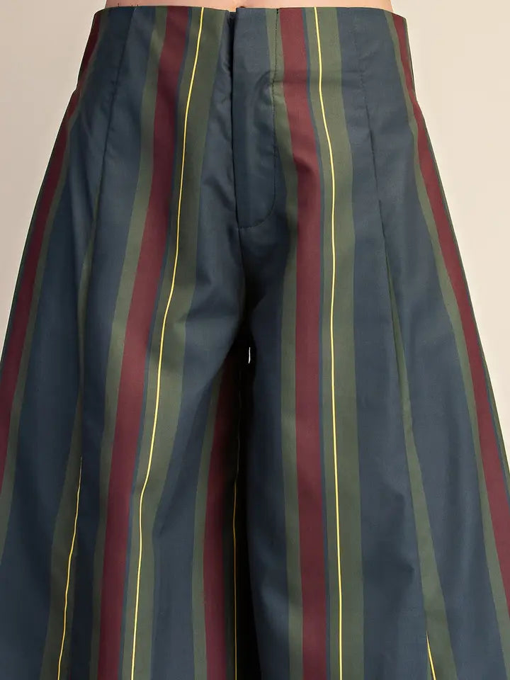 Close-up of pleated trousers with vertical stripes in navy blue, burgundy, olive green, and thin yellow lines.