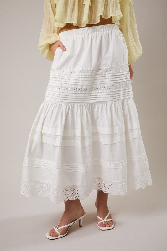 White lace skirt worn with a yellow top on a plain background