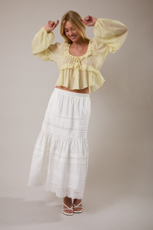 Woman wearing a yellow blouse and white skirt against a plain background