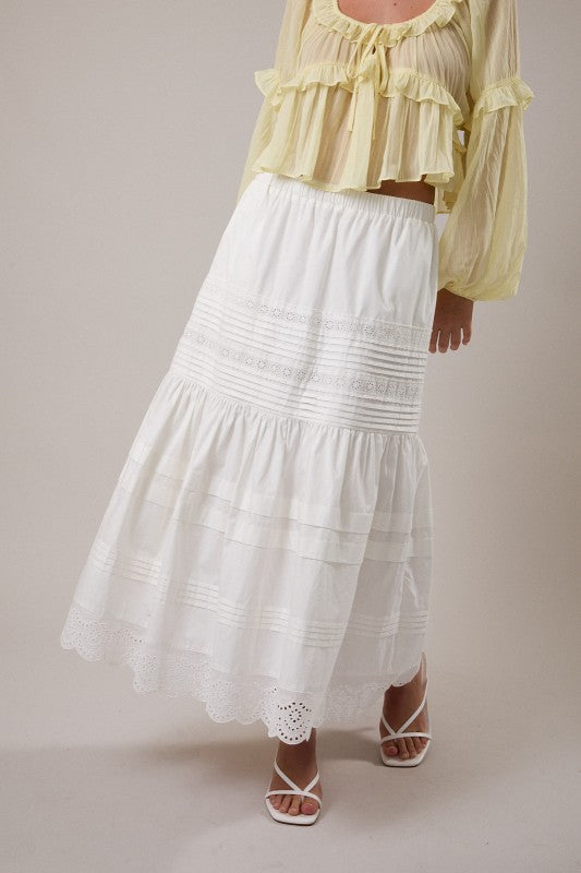 Woman wearing a yellow blouse and white skirt on a plain background