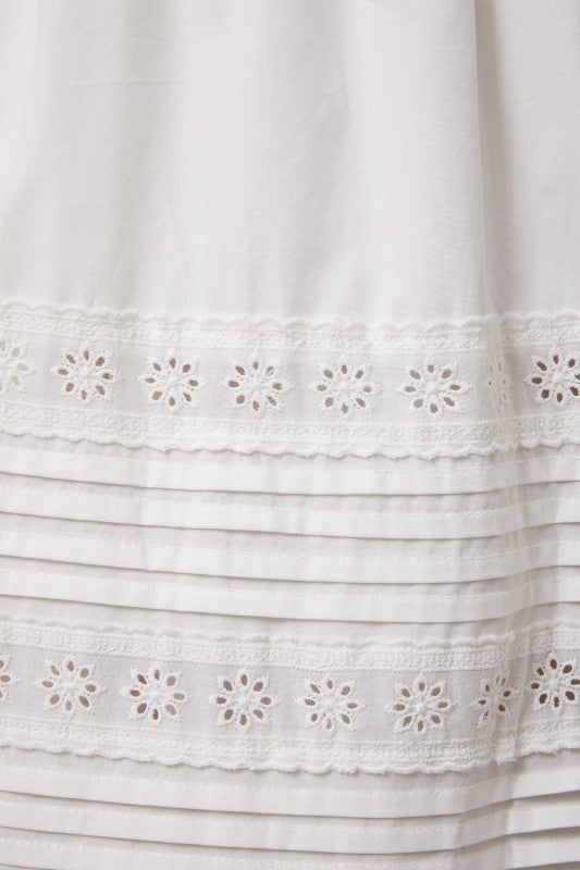 Close-up of a white dress with floral lace details on a white background