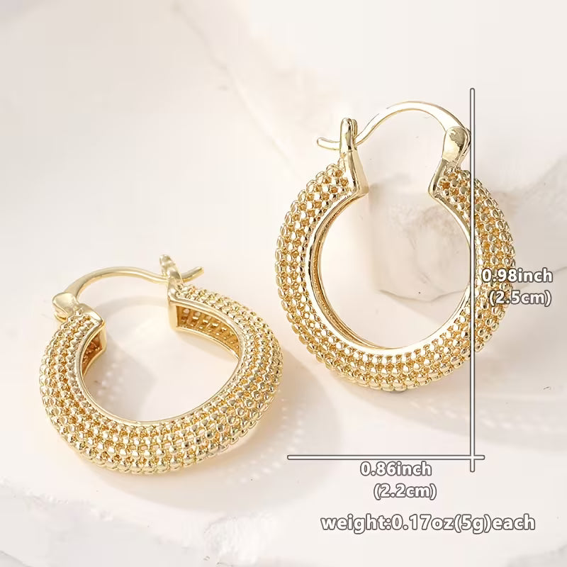 Gold hoop earrings with a textured, beaded outer band and leverback closures, shown on a light marble surface with dimension and weight annotations.