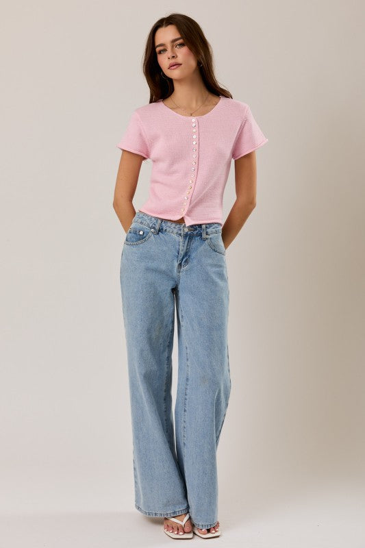 Woman wearing a pink top and blue jeans on a plain background
