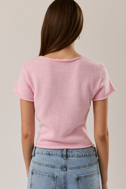 Person wearing a pink textured t-shirt and blue jeans on a plain background