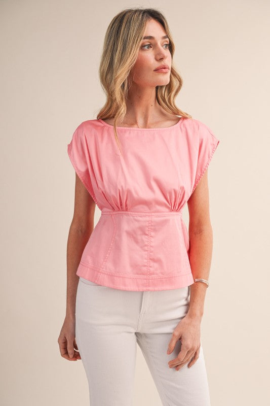 Woman wearing a pink top and white pants on a beige background